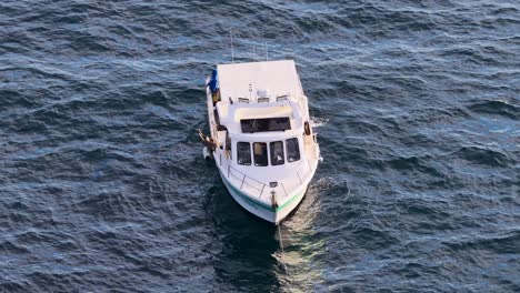 aerial footage of a commercial fishing boat cruising on open ocean waters near gold coast, australia, captured in soft natural sunset lighting