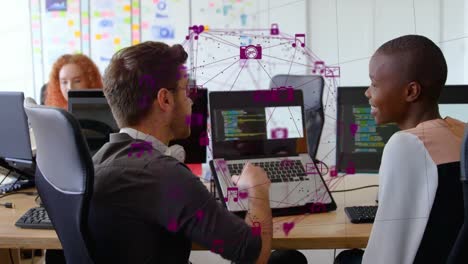 Animation-of-globe-of-digital-icons-over-diverse-man-and-woman-discussing-over-a-laptop-at-office