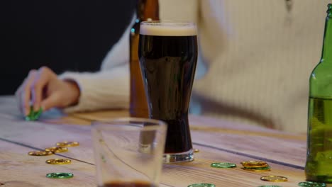 close up of friends at home or in bar celebrating at st patrick's day party drinking alcohol and playing with novelty gold coins 1