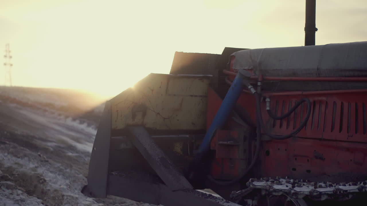 Trattore in un campo innevato al tramonto