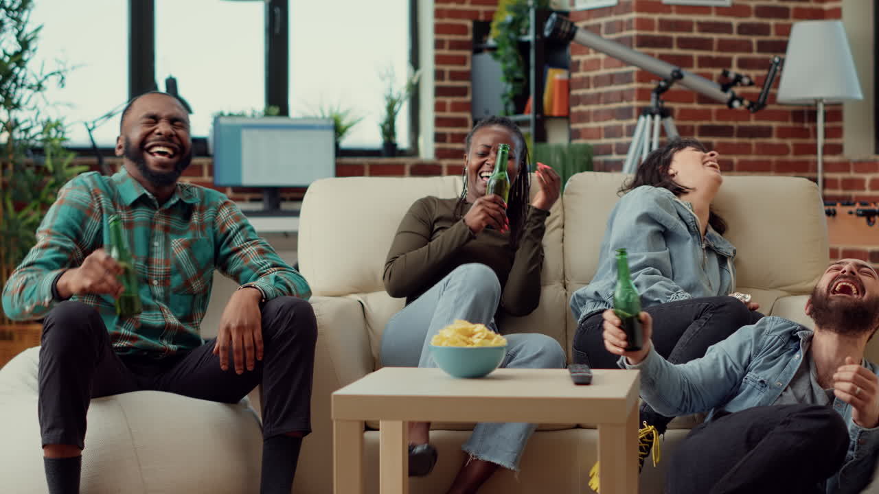 Cheerful friends watching comedy movie on tv and laughing