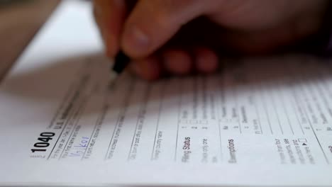 man filling us tax form. tax form us business income office hand fill concept. closeup.  man is checking the box of filing status in the us individual income.  tax return form 1040