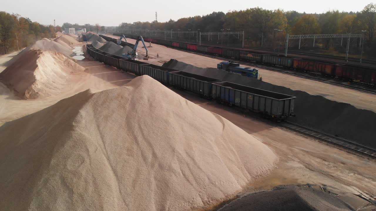 Aerial establishing shot of a big gravel rail terminal with heavy machinery working