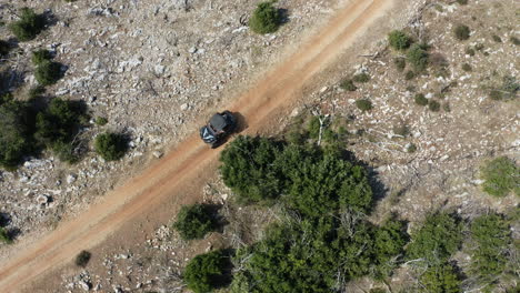 tracking aerial shot of beach buggy on dryland path, birds eye view