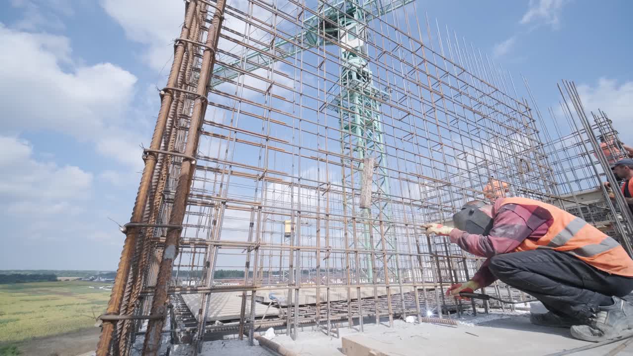 Construction worker welding metal rebar for the pouring of monolithic structure