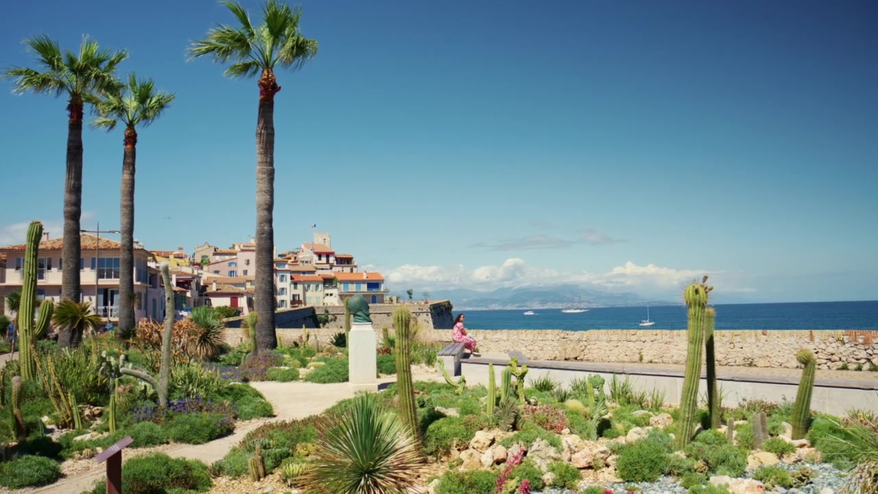 Giardino di cactus mediterraneo con palme, piante grasse e vista mare lungo la Promenade Amiral de Grasse nella Vecchia Antibes, Francia, che si affaccia sulla costa della Costa Azzurra, Antibes, Francia.