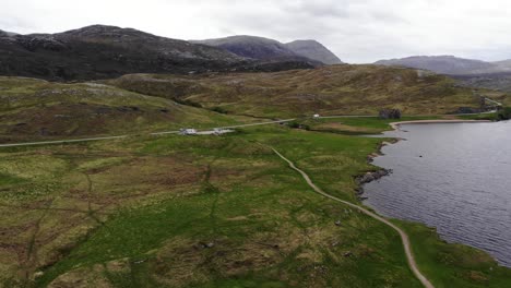 aerial descending shot from loch assynt looking towards the mountains of the scottish highlands