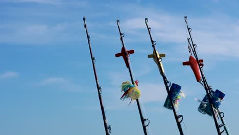 fishing rods with colorful lures sway gently against a clear blue sky in phuket, thailand. bright daylight enhances the vivid colors