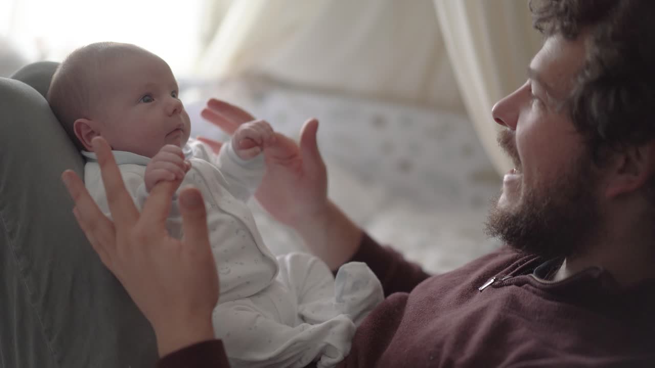 Far leker og snakker med nyfødt baby hjemme