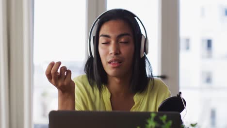 mixed race gender fluid person recording a podcast using laptop at home