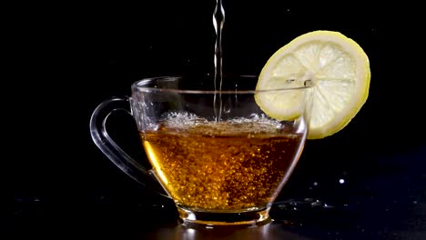 a stream of tea fills a glass cup with a lemon slice, set against a dark backdrop
