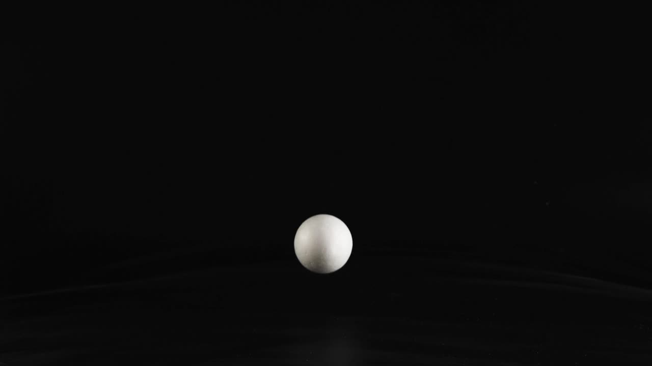 A hand drops a styrofoam ball