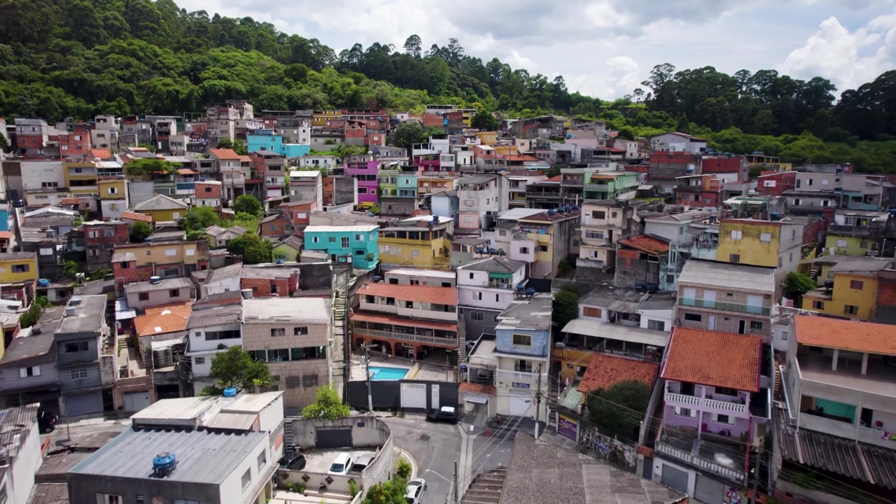 Drone che vola basso dirigendosi verso un quartiere modesto con case colorate a São Paulo, Brasile