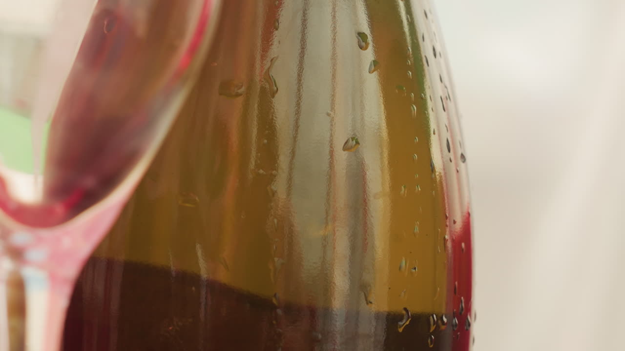 closeup green wine bottle with glass, droplets and condensation on curved shoulder, soft bokeh background, refined dining atmosphere with anticipation before pour, bright elegant tasting scene
