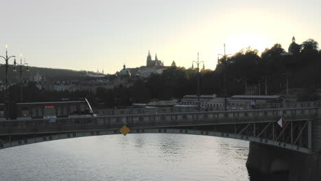 Modern-streetcar-crossing-a-bridge,Vltava-river,sunset,Prague,Czechia