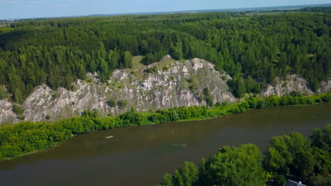 river flowing through a lush green forest with rocky cliffs
