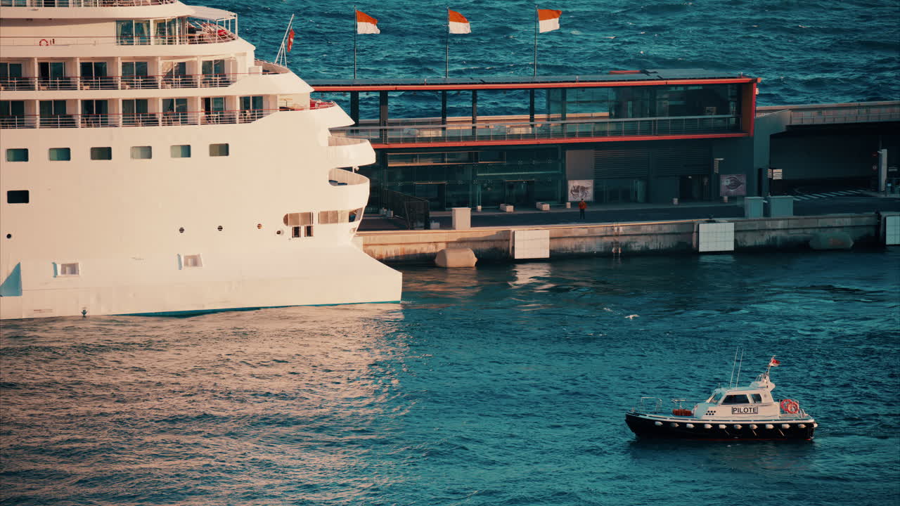 Monte Carlo, Monaco - October 14, 2024: Small boat moving on the sea near a large cruise ship docked in the Monaco Marina in the evening