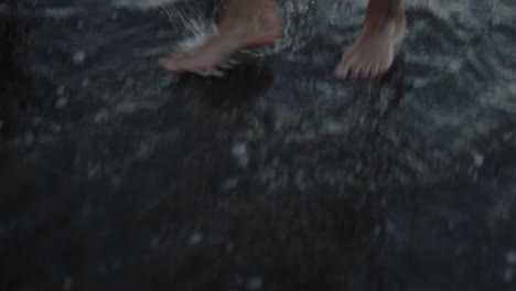 Handheld-shot-looking-down-onto-male-maori-feet-with-tribal-tattoo-on-leg-walking-along-the-shoreline-of-black-sand-Bethells-beach-in-Auckland-New-Zealand