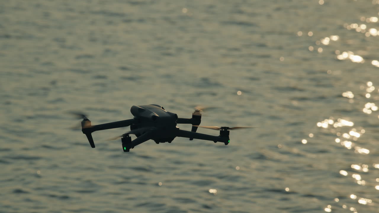 Drone che vola sulla superficie del mare con riflessi della luce solare al tramonto.