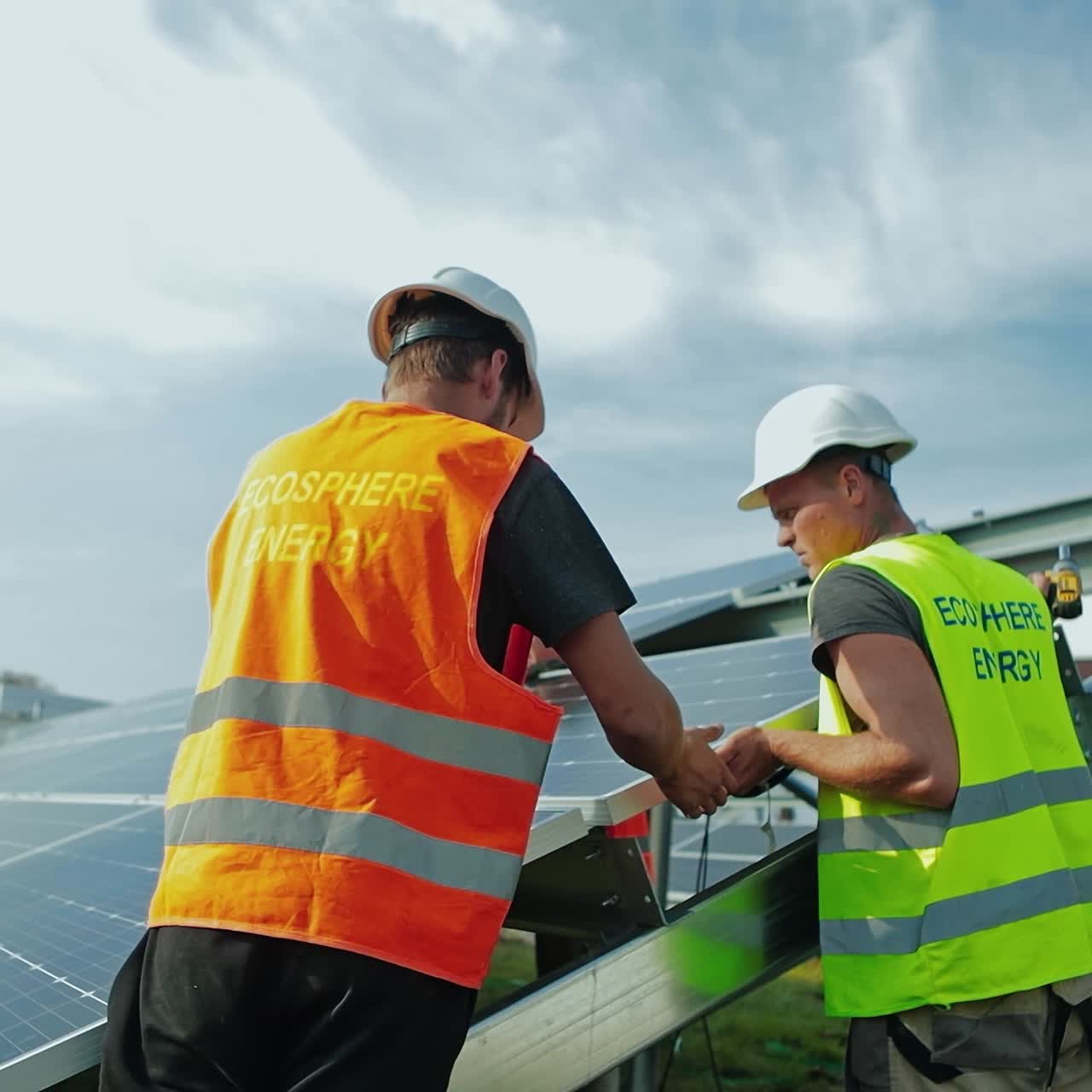 Workers in special uniform installing solar batteries. Men in protective helmets constructing solar panels in a sunny day. Alternative source of energy.