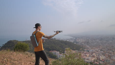 videógrafo de viajes hombres volando aviones no tripulados desde la mano sobre el paisaje urbano en el fondo