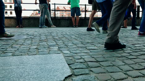 la gente camina en una acera llena de gente, cierra la vista de la acera y las piernas a la altura de la rodilla, cámara lenta en zapatos y pasos