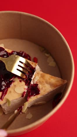 healthy cheesecake slice with berries and almonds in a paper container