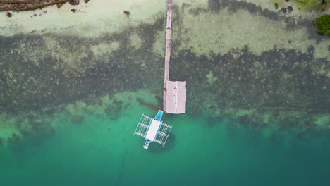 top down rising perspective of bangka outrigger canoe at wooden pier, aerial