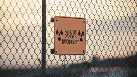 Close-up-of-Nuclear-Radiation-Danger-Sign-on-Barbed-Wire-Perimeter-Fence-with-Contaminated-Airborne-Radioactive-Particles-in-Exclusion-Zone-Slow-Motion-4K