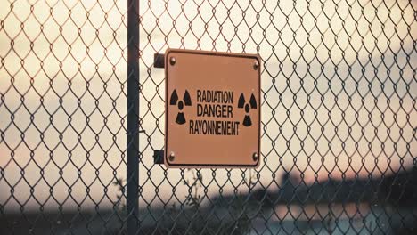 primer plano de la señal de peligro de radiación nuclear en la valla perimetral de alambre de púas con partículas radiactivas contaminadas en el aire en la zona de exclusión a cámara lenta 4k