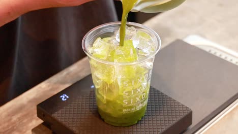 pouring matcha over ice in a cup