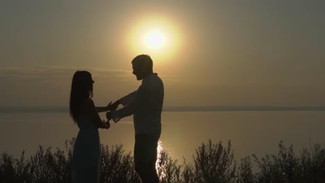 couple holding hands at sunrise/sunset by the lake