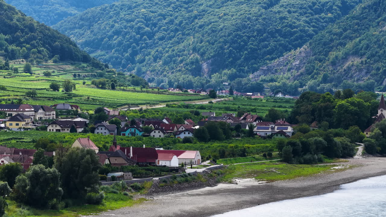 Aşağı Avusturya'da, üzüm bağları ve küçük köylerle çevrili, doğal güzellikleriyle ünlü Wachau Vadisi boyunca Tuna Nehri'nde seyreden bir kargo gemisinin sinematik hava drone çekimi.