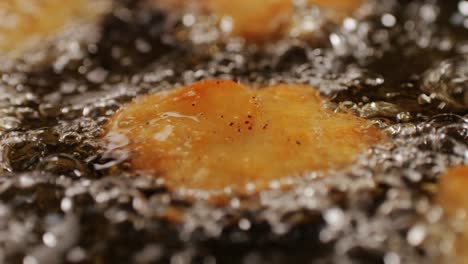 american chiken nuggets broiling on black frying pan close-up macro. breaded nagget of chiken meat. man cooking fast food. high quality 4k footage