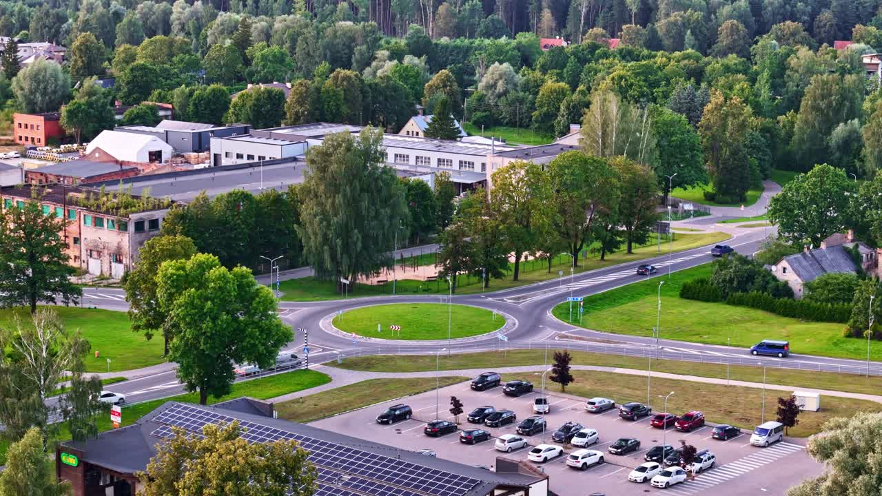 Roundabout in Ozolnieki town with buildings and trees on sunny summer evening in aerial view