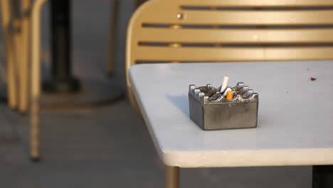 ashtray with cigarette butts on a table outside