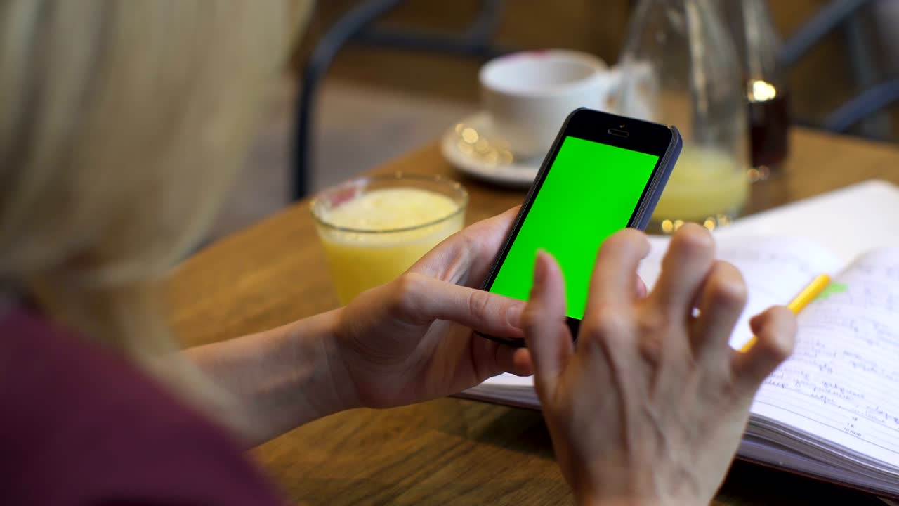 mujer de negocios usando un teléfono inteligente en una cafetería. teléfono inteligente con pantalla verde