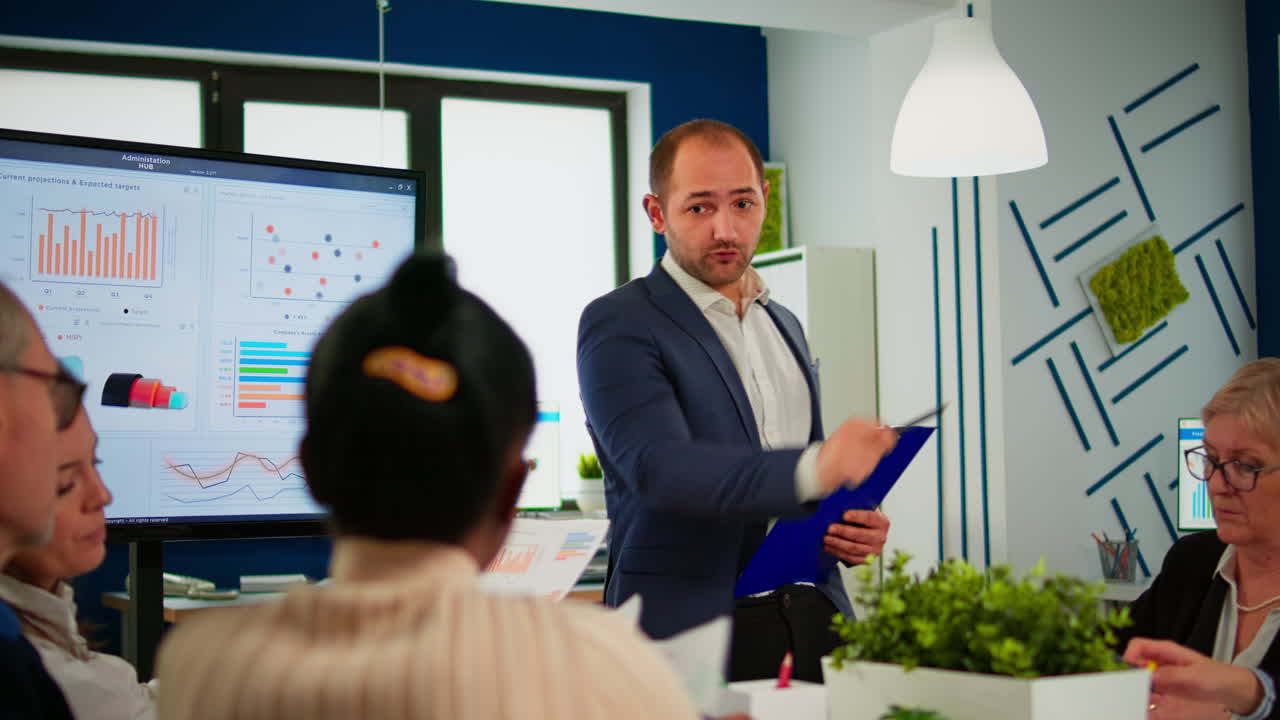 Comapany CEO holding clipboard and pointing on digital interactive whiteboard
