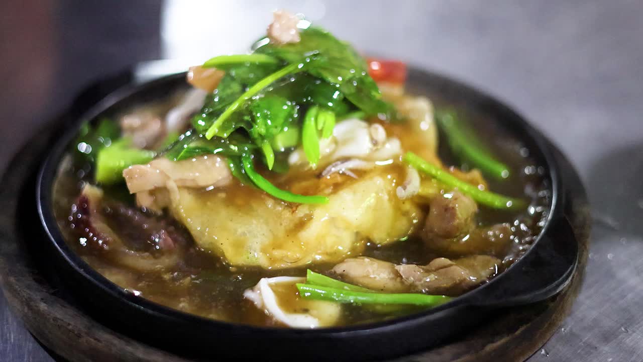 Steaming fried noodles with vegetables and meat on hot plate, vibrant street food, shallow focus