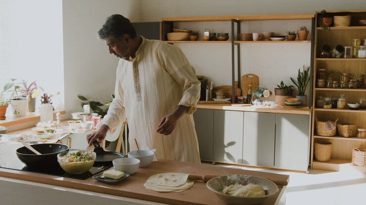 Uomo indiano che cucina Roti in una cucina moderna