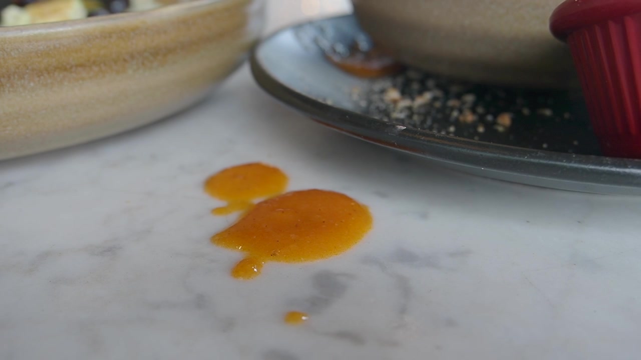 Close-Up of Spilled Orange Sauce on a Marble Table