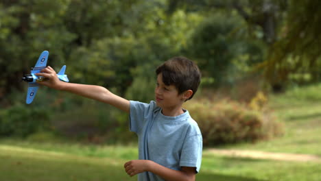 Kleiner-Junge-Spielt-Mit-Einem-Spielzeugflugzeug-Im-Park