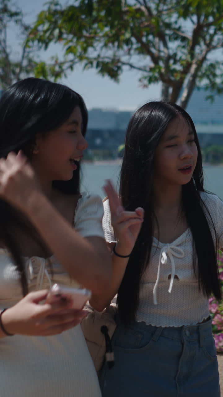 หญิงสาวเอเชียรุ่นใหม่มีความสุขกับการแชทและใช้โทรศัพท์กลางแจ้ง