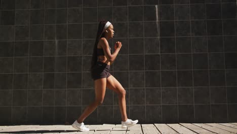 African-american-woman-exercising-outdoors-wearing-wireless-earphones-stretching-in-the-city