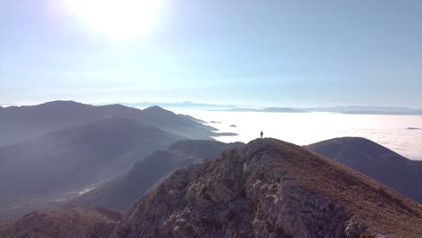 drone shot of a hiker standing on top of a mountain