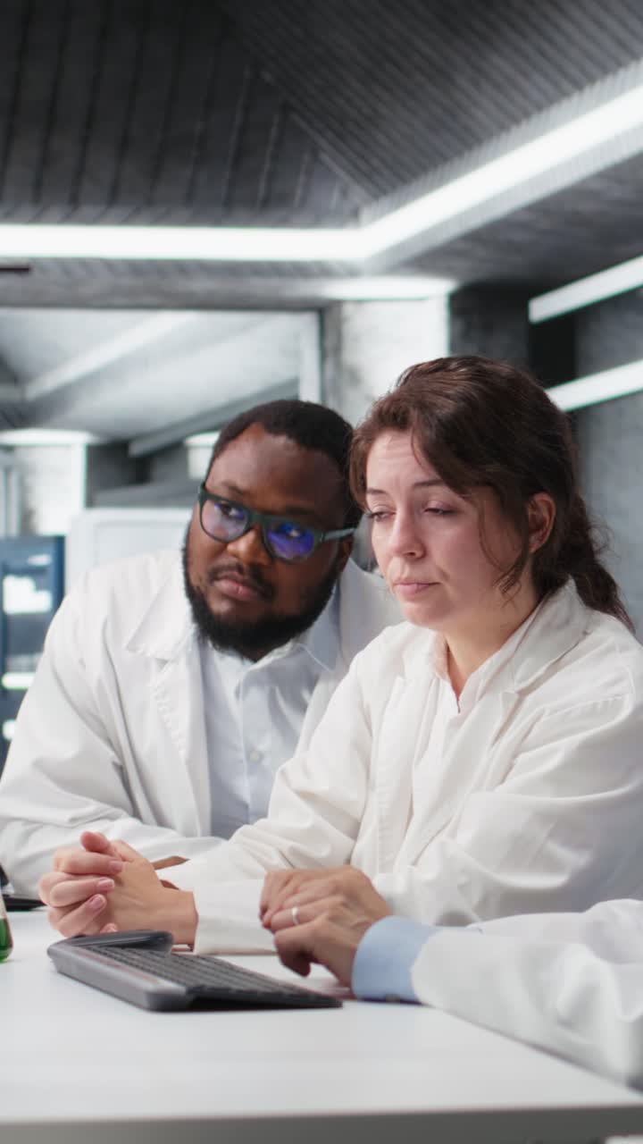 Vertical video Multiracial lab technicians at PC desk looking at 3D molecular model