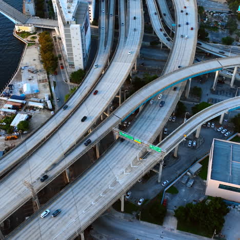 Intertwining freeways with cars moving by. Two motor boats sail by the river in Miami under drawbridge. Top view.