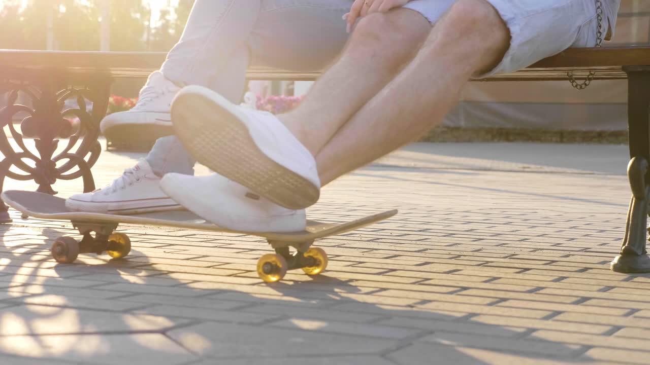 Couple Relaxing on a Park Bench with Skateboard