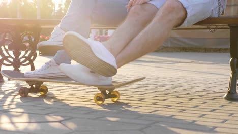 couple relaxing on a park bench with skateboard