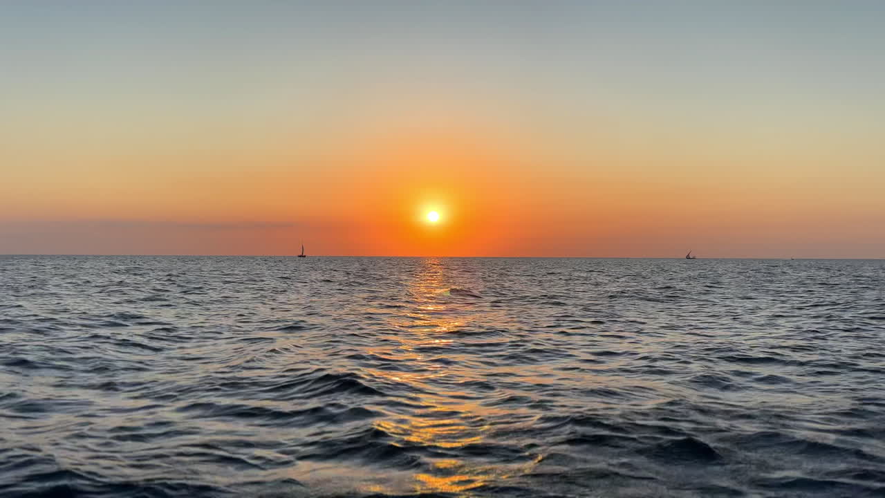 Sunset over the ocean with sailboats